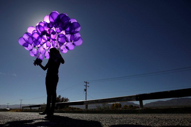 An activist holds purple balloons at El Navajo creek, where the bodies of several women were found, during a ceremony to mark the International Day for the Elimination of Violence Against Women on the outskirts of Ciudad Juarez, Mexico.