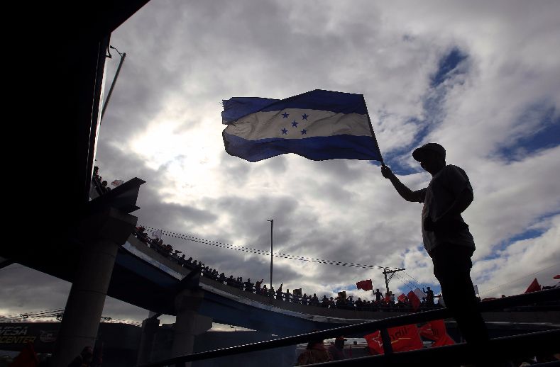 A supporter of Nasralla raises the Honduran flag as election results are awaited.