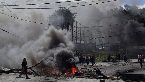 An opposition supporter passes a burning barricade during a protest caused by the delayed vote count for the presidential election in Honduras.