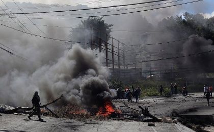 An opposition supporter passes a burning barricade during a protest caused by the delayed vote count for the presidential election in Honduras.