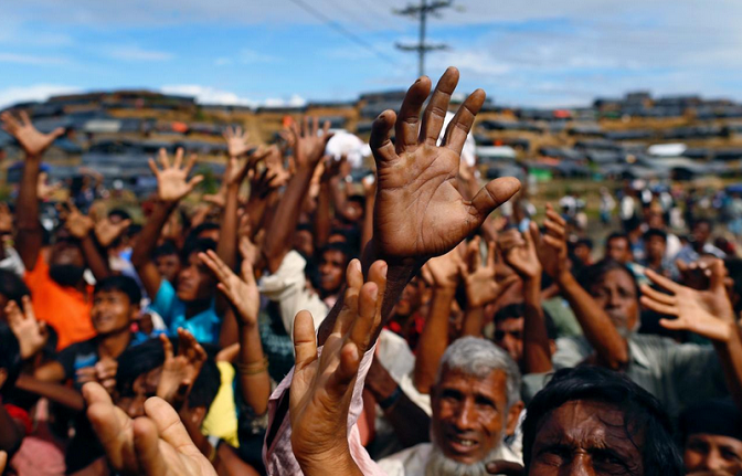 Rohingya refugees stretch their hands to receive aid distributed by local organisations at Balukhali makeshift refugee camp in Cox's Bazar, Bangladesh.