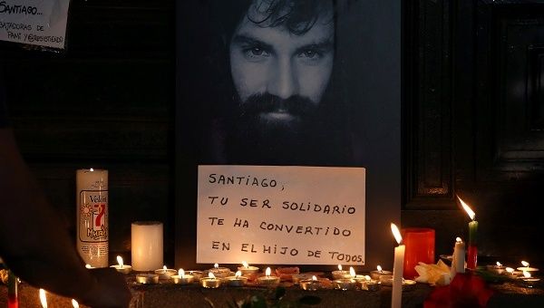 A man lights candles next to a portrait of Santiago Maldonado, who went missing after security forces clashed with indigenous activists in Patagonia on August 1.