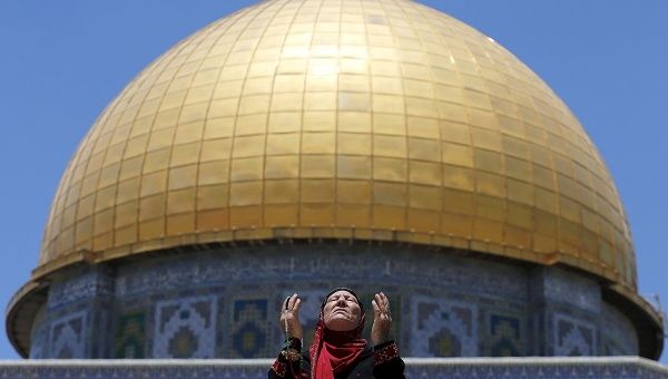 A Palestinian woman prays in front of the Dome of the Rock in Jerusalem's Old City.