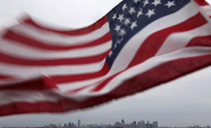 A U.S. flag flutters against the skyline of New York and Jersey City.