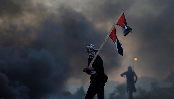 A demonstrator holds a Palestinian flag during clashes with Israeli troops after Trump's decision to recognize Jerusalem as Israel's capital.