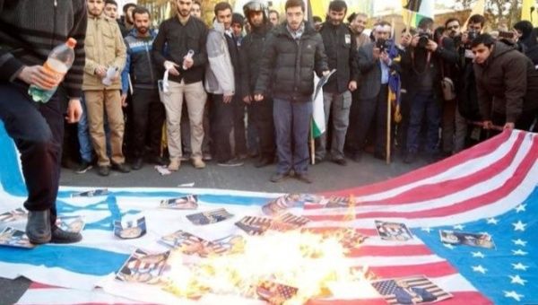 Iranians burning photos on a flag at a rally protesting Israel.