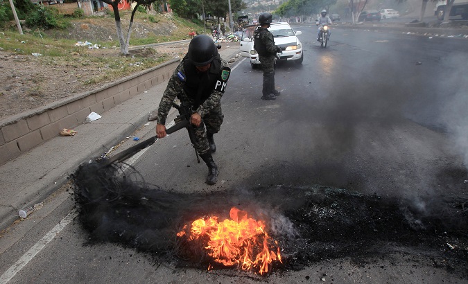 A military police removes a burning tire from a barricade settled by opposition supporters during a protest, in Tegucigalpa, Honduras December 18, 2017.