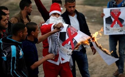 A Palestinian demonstrator dressed as Santa Claus burns a poster depicting U.S. President Donald Trump during Dec. 19, 2017. 