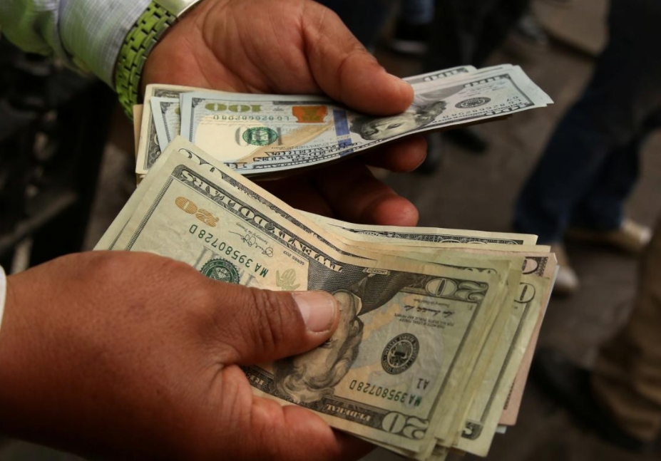 A money changer holds U.S. dollar bills at a street in downtown Lima, Peru.