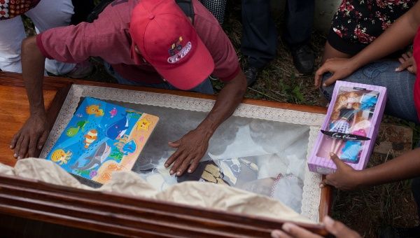 Alexander Conopoy reacts over the coffin of his daughter Alexandra Conopoy, a pregnant 18 year-old killed in Charallave, Venezuela Jan. 1, 2018.