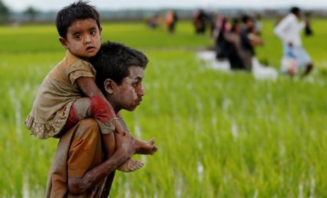 A Rohingya boy carries a child after after crossing the Bangladesh-Myanmar border in Teknaf, Bangladesh.
