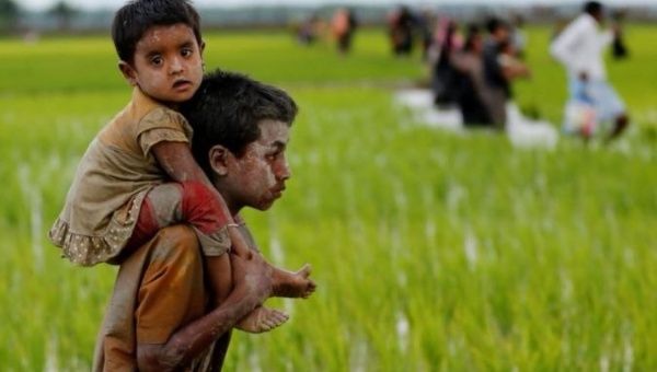 A Rohingya boy carries a child after after crossing the Bangladesh-Myanmar border in Teknaf, Bangladesh.