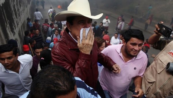 Honduras' former President Manuel Zelaya covers his mouth to protect himself from smoke during a protest against the re-election of Honduran President Juan Orlando Hernandez in Tegucigalpa, Honduras January 21, 2018