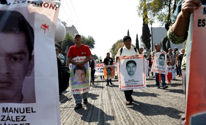 Relatives holding posters with images of some of the 43 missing students of Ayotzinapa teacher's training college.
