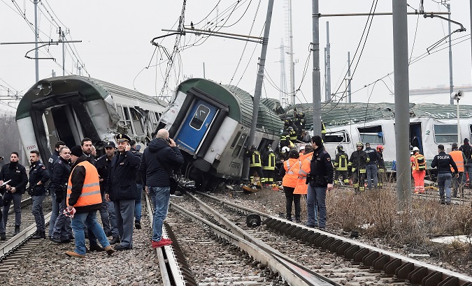 Rescue workers and police officers stand near derailed trains in Pioltello, on the outskirts of Milan, Italy, Jan. 25, 2018.