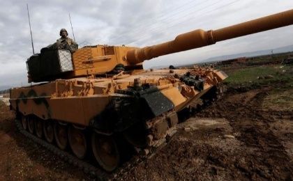 A Turkish soldier sits on a tank as Turkish troops prepare near the Syrian-Turkish border at Reyhanli district in Hatay, Turkey.