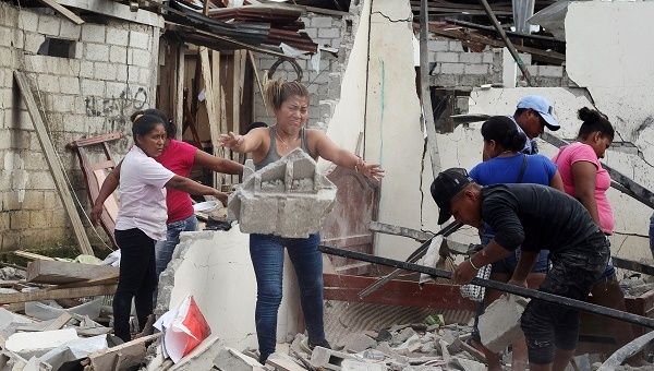 People remove debris from their damaged houses next to the scene of a bomb explosion at a police station in San Lorenzo, Ecuador.