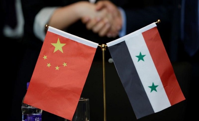 Chinese and Syrian businessmen shake hands behind their national flags during a meeting to discuss reconstruction projects in Syria.