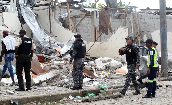 Police officers walk at the scene of a bomb explosion at a police station in San Lorenzo, Ecuador.