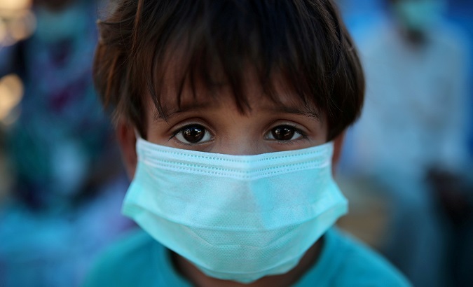 A Rohingya refugee child wears a mask as he waits for medical checkup in Samaritan's Purse diphtheria clinic in Cox's Bazar, Bangladesh, January 21, 2018.