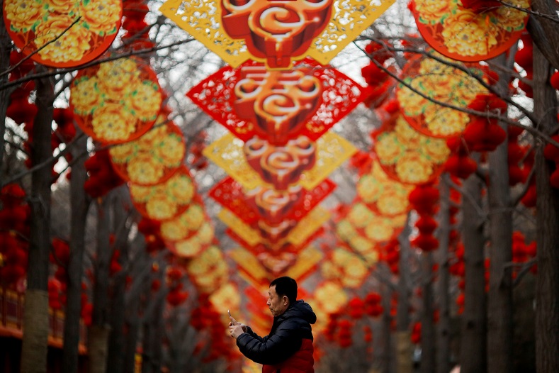 Wandering through a forest of trees decked in cherry red and bright yellow, a man strolls beneath a wave of decorations for the Spring Festival, or Chinese Lunar Festival, in Beijing, China.
