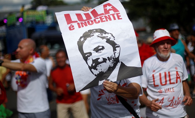 A reveller holds a poster of former Brazil's President Luiz Inacio Lula da Silva that reads: 