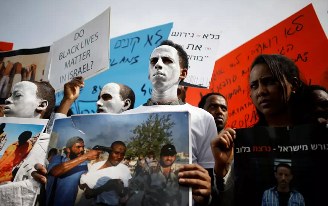 African migrants painted in white hold signs during a protest against the Israeli government's plan to deport part of their community, in front of the Rwandan embassy in Herzliya, Israel.