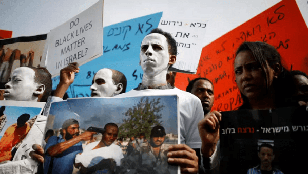 African migrants painted in white hold signs during a protest against the Israeli government's plan to deport part of their community, in front of the Rwandan embassy in Herzliya, Israel. 