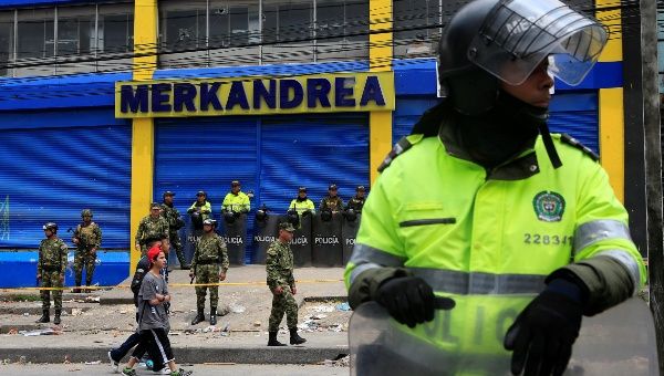 Colombian police and soldiers guard a supermarket allegedly linked to FARC in Bogota, Colombia, after it was sacked by looters. 