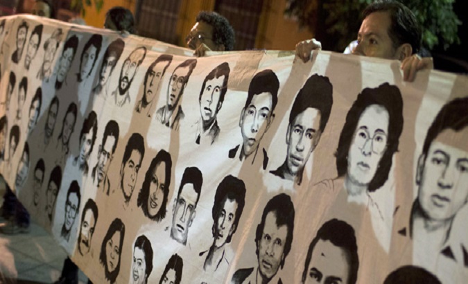 A group of people hold a banner with photographs of missing people in Guatemala.