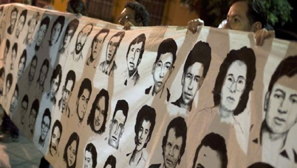 A group of people hold a banner with photographs of missing people in Guatemala.