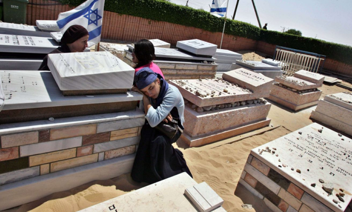 Israelis mourn next to graves of relatives in a cemetery, before the exhumation of graves as part of Israel's disengagement from Gaza in 2005.