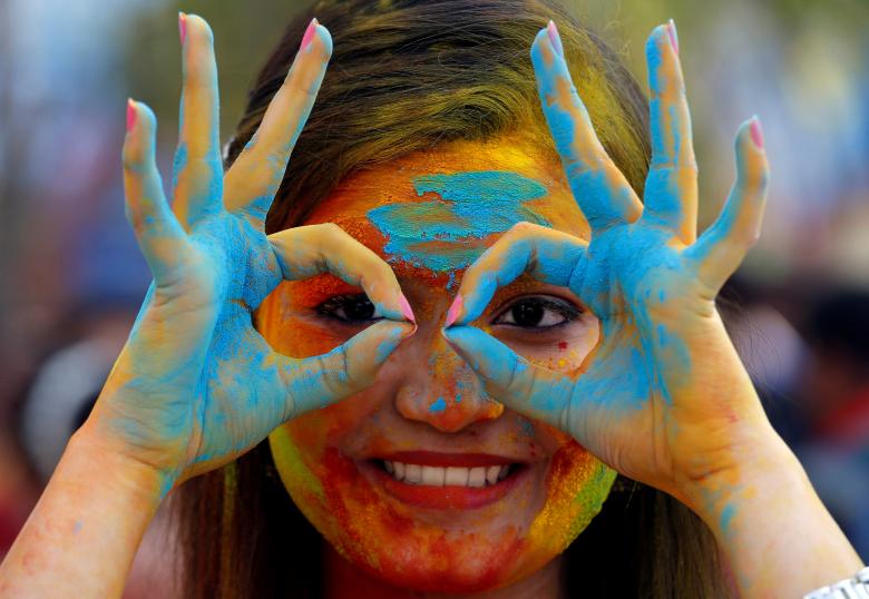 A student of Rabindra Bharati University, with her face smeared in colored powder, poses during celebrations for Holi inside the university campus in Kolkata, India, February 26, 2018.