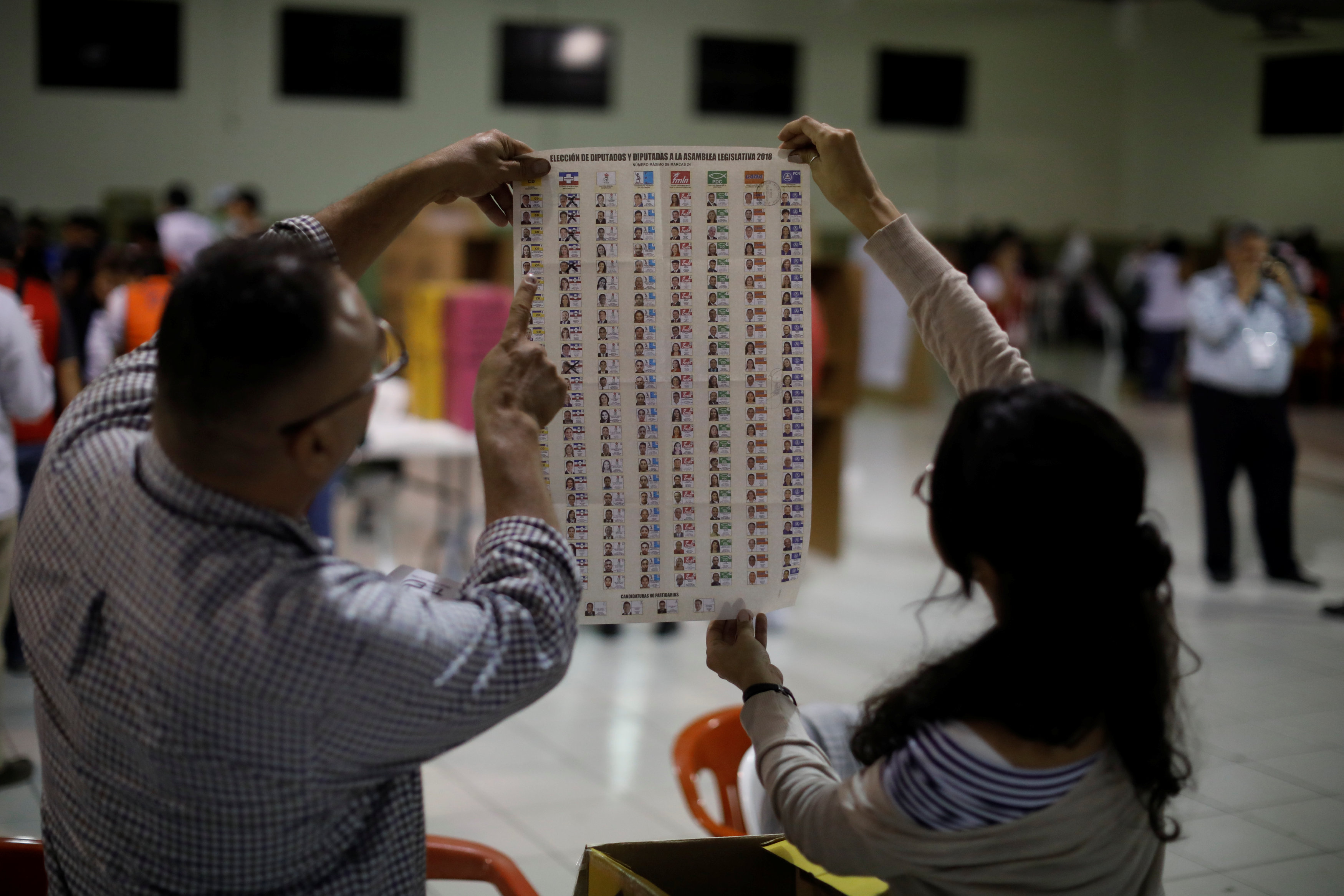 A Salvadoran electoral official holds up a ballot as he and his colleagues prepare to count them.