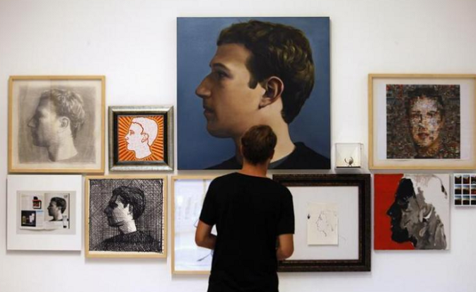 A visitor looks at portraits of Facebook's founder Mark Zuckerberg at solo exhibition 