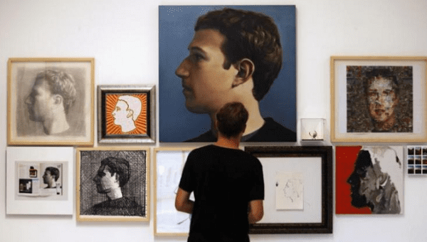 A visitor looks at portraits of Facebook's founder Mark Zuckerberg at solo exhibition 
