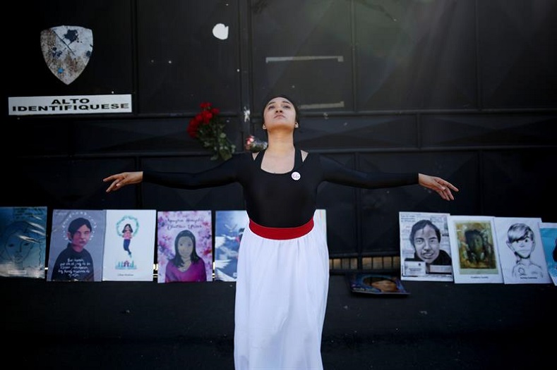 An artist dances in front of paintings commemorating the 41 victims.