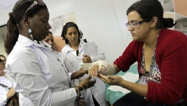 Cuban doctor Yoselin Macias (L) helps bandage a pateint's arm.