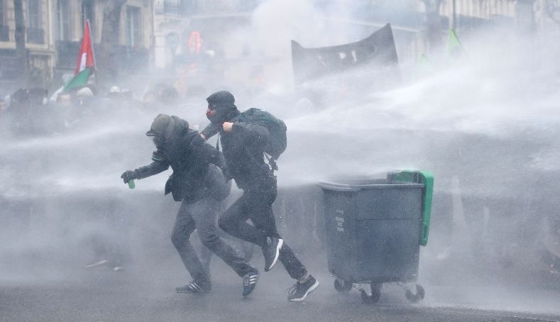 French riot police use water cannons during clashes with masked protesters attending a demonstration during a national day of strike against reforms in Paris, France.