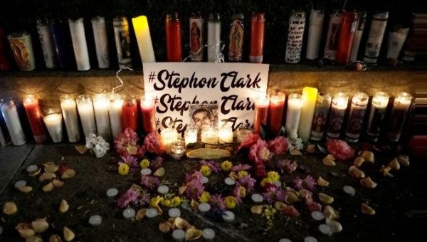 Candles light a sidewalk memorial for Stephon Clark.