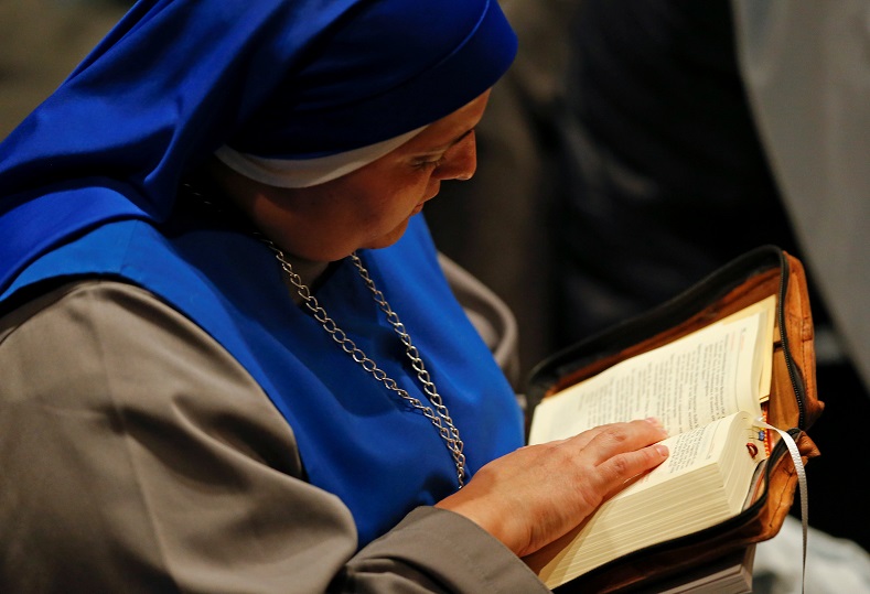 A nun reads the book of the gospels before the start of the Easter vigil mass led by Pope Francis in Saint Peter's Basilica at the Vatican, March 31.