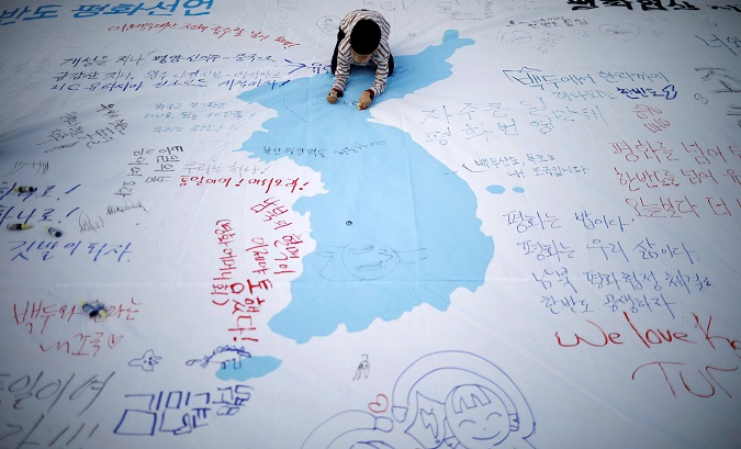 A child writes a message on a unification flag wishing for a successful inter-Korean summit during a rally in central Seoul, South Korea.