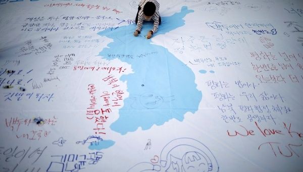 A child writes a message on a unification flag wishing for a successful inter-Korean summit during a rally in central Seoul, South Korea.