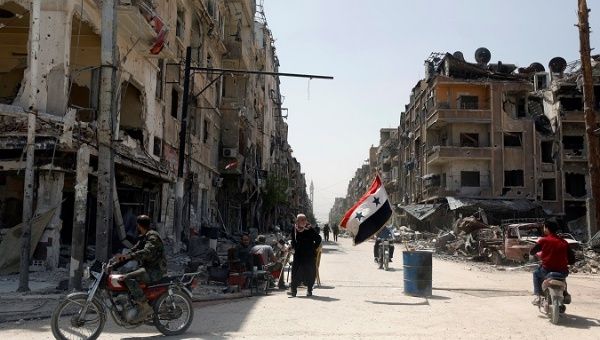 A Syrian flag flutters in the wind on a war-ravaged street in the city of Douma in Damascus, Syria.