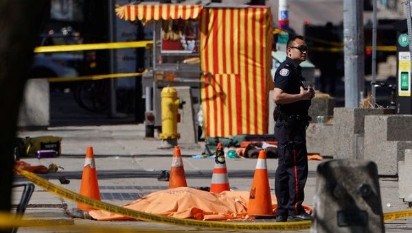 A police officer stands next to a victim of an incident where a van struck multiple people at a major intersection in Toronto's northern suburbs in Toronto.