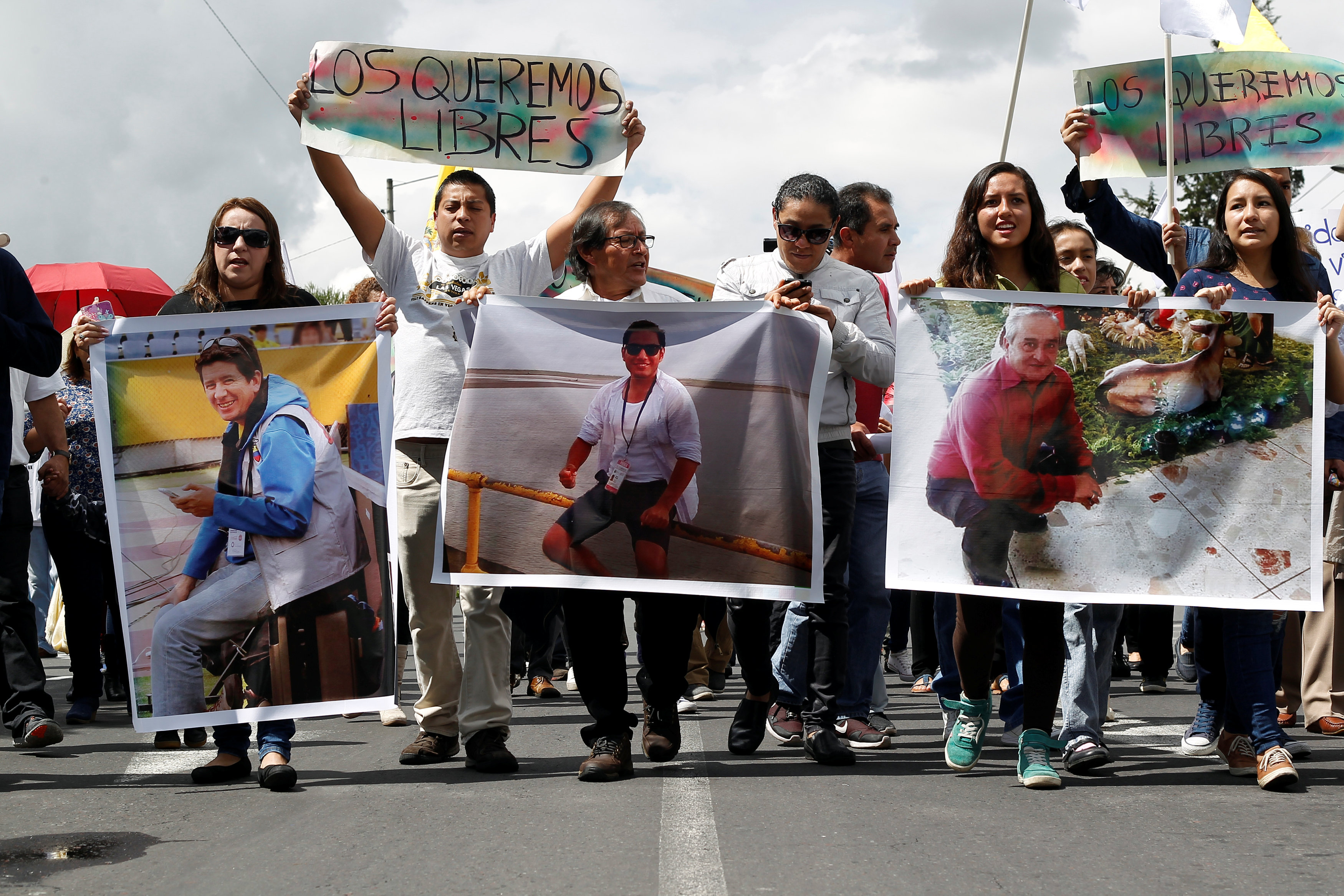 Relatives and friends hold pictures of Ecuadorean photojournalist Paul Rivas (left), journalist Javier Ortega (center) and their driver Efrain Segarra during a protest march to demand their release, in Quito, Ecuador April 1, 2018.