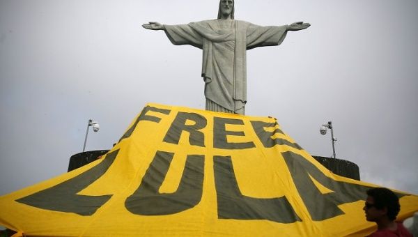 Supporters of Luiz Inacio Lula da Silva hoist a banner in front of the statue of Christ the Redeemer in Rio de Janeiro, April 14, 2018.