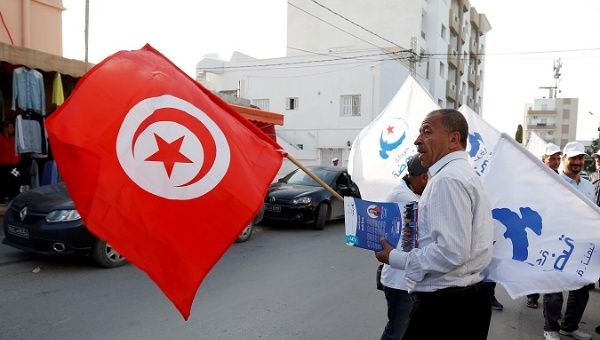A supporter of the Islamist Ennahda Party waves the national flag, as he distributes municipal elections leaflets in Tunis, Tunisia April 28, 2018.