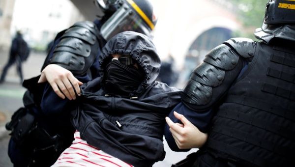 French riot police apprehend a masked and hooded protester after clashes at a demonstration during a national day of strikes by public sector workers in Paris