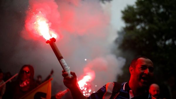 A protester holds a safety flare during the demonstration for a national day of strikes by public sector workers in Paris